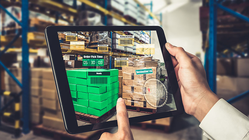 Warehouse worker using augmented reality technology on a tablet.