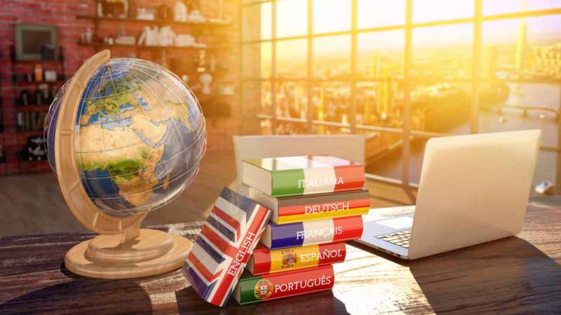 A laptop, a stack of language books, and a globe.