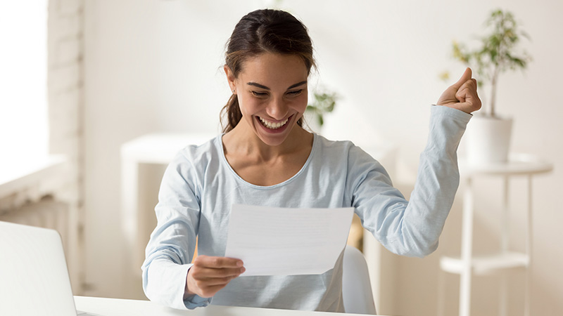 A smiling woman reading a document.