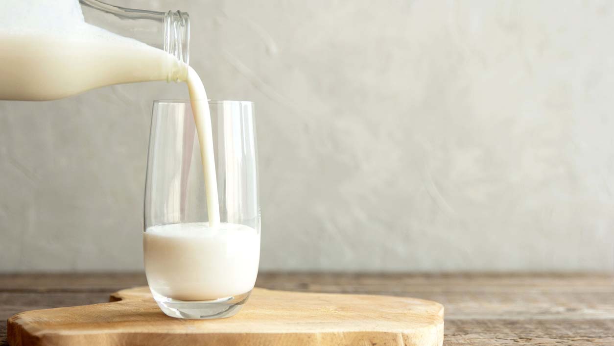 A jug of milk filling a glass.