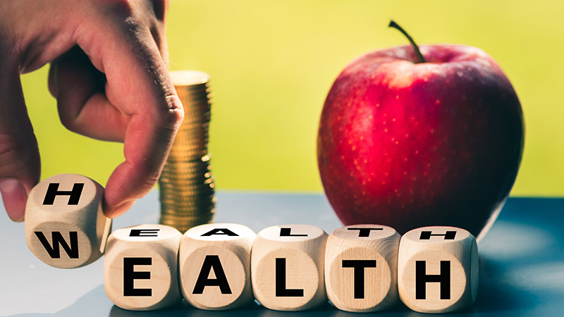 Person changing wooden blocks from 'wealth' to 'health.'