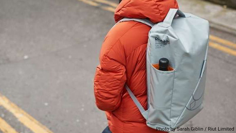 Person in orange coat wearing a Riut backpack. 