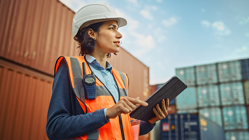 Industrial engineer with a tablet working in a shipping yard.