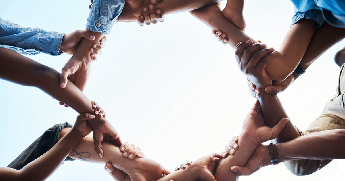 Group of businesspeople holding arms in a circle.
