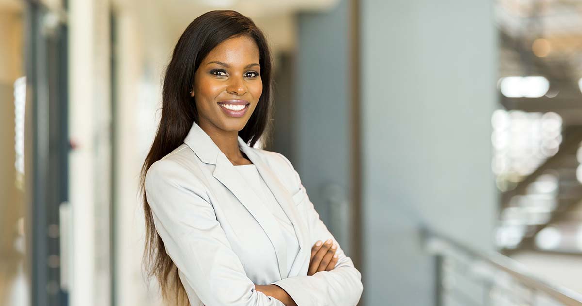 Businesswoman in a suit standing confidently with her arms crossed.
