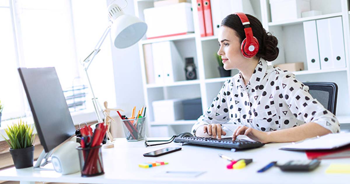 https://startupsavant.comSmiling woman at desk working at computer with headphones